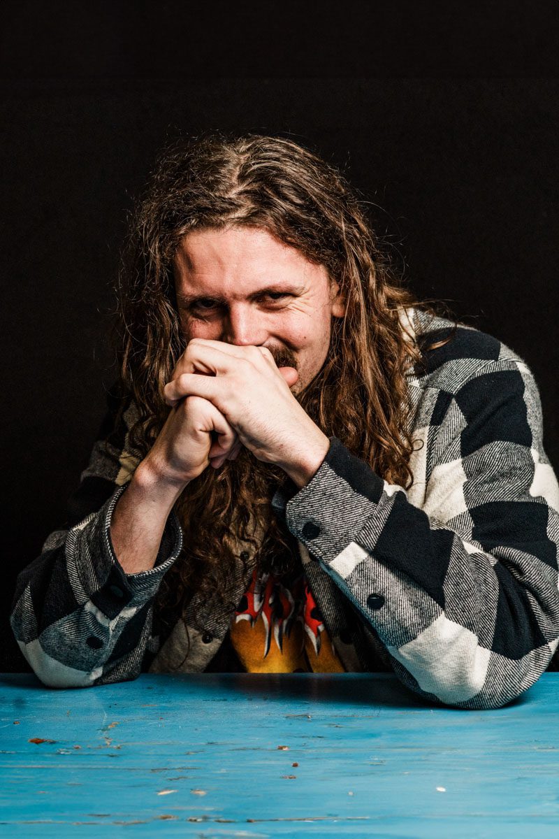 A metalhead with long hair sitting at a table.