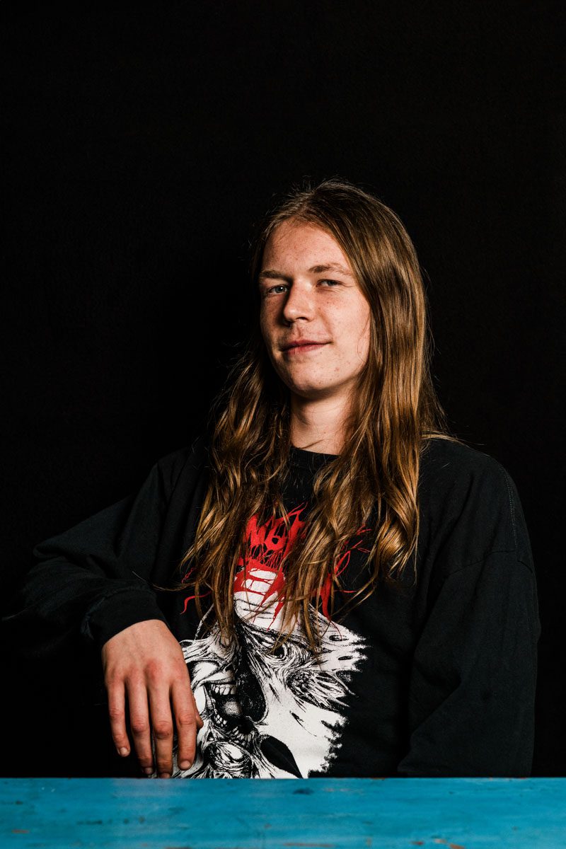 A metalhead with long hair sitting at a table.