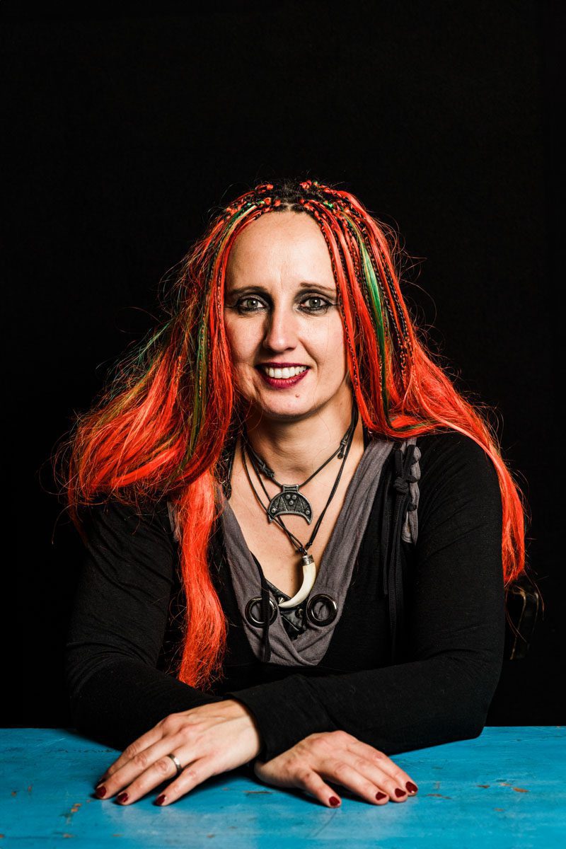 A femal metalhead with long hair sitting at a table.