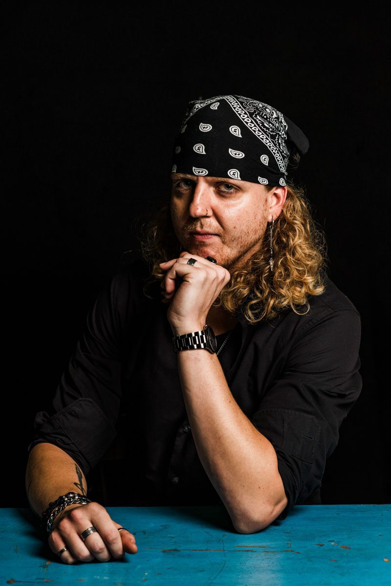 A metalhead with long hair sitting at a table.