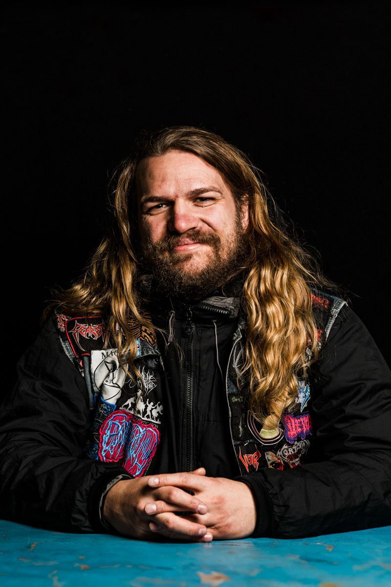 A metalhead with long hair sitting at a table.