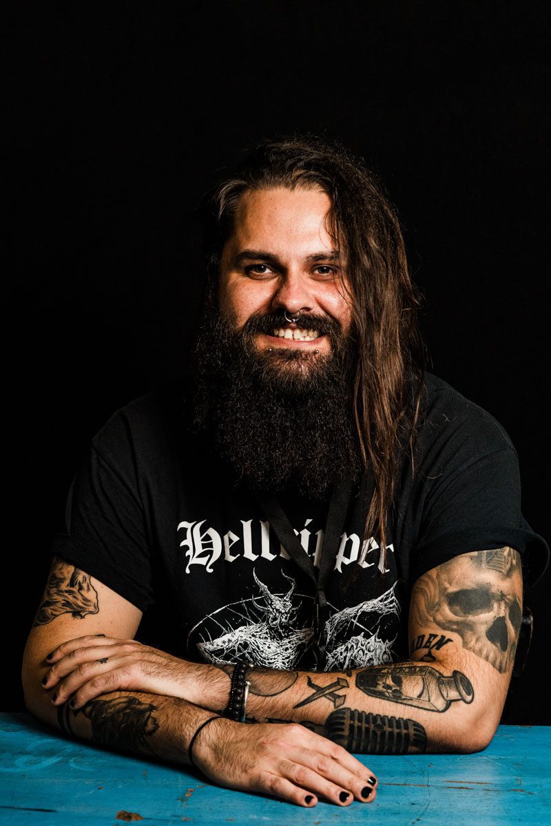 A metalhead with long hair sitting at a table.