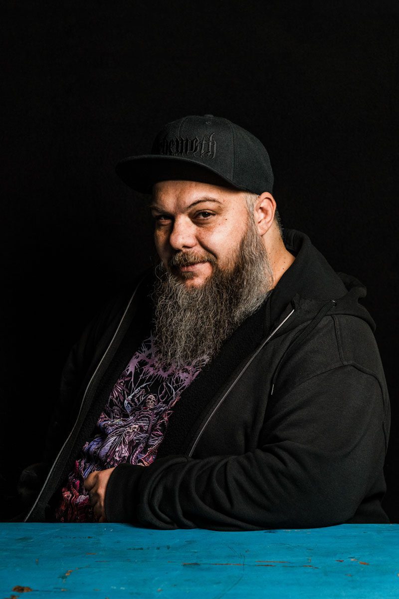 A metalhead with long beard sitting at a table.