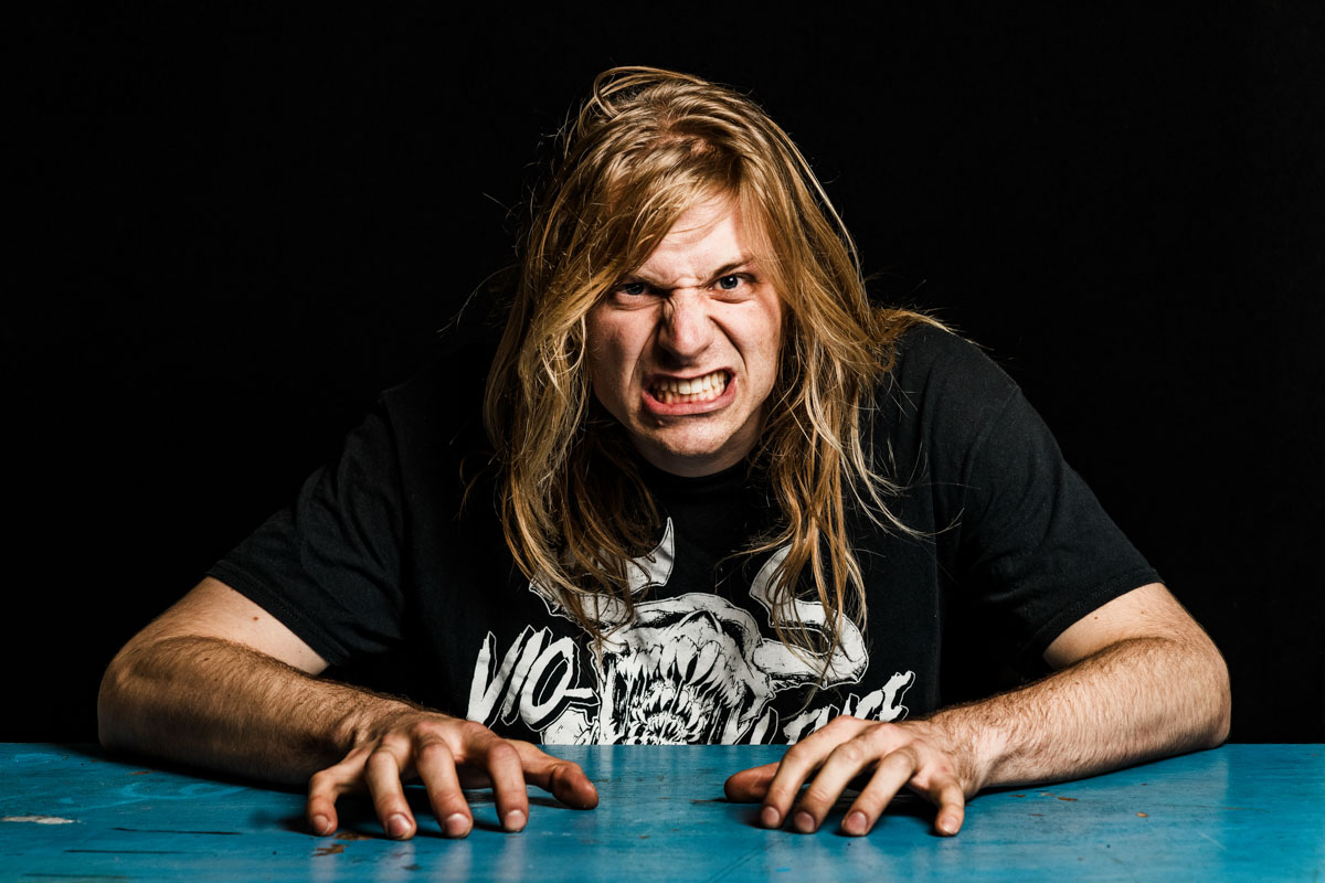 A metalhead with long hair sitting at a table.