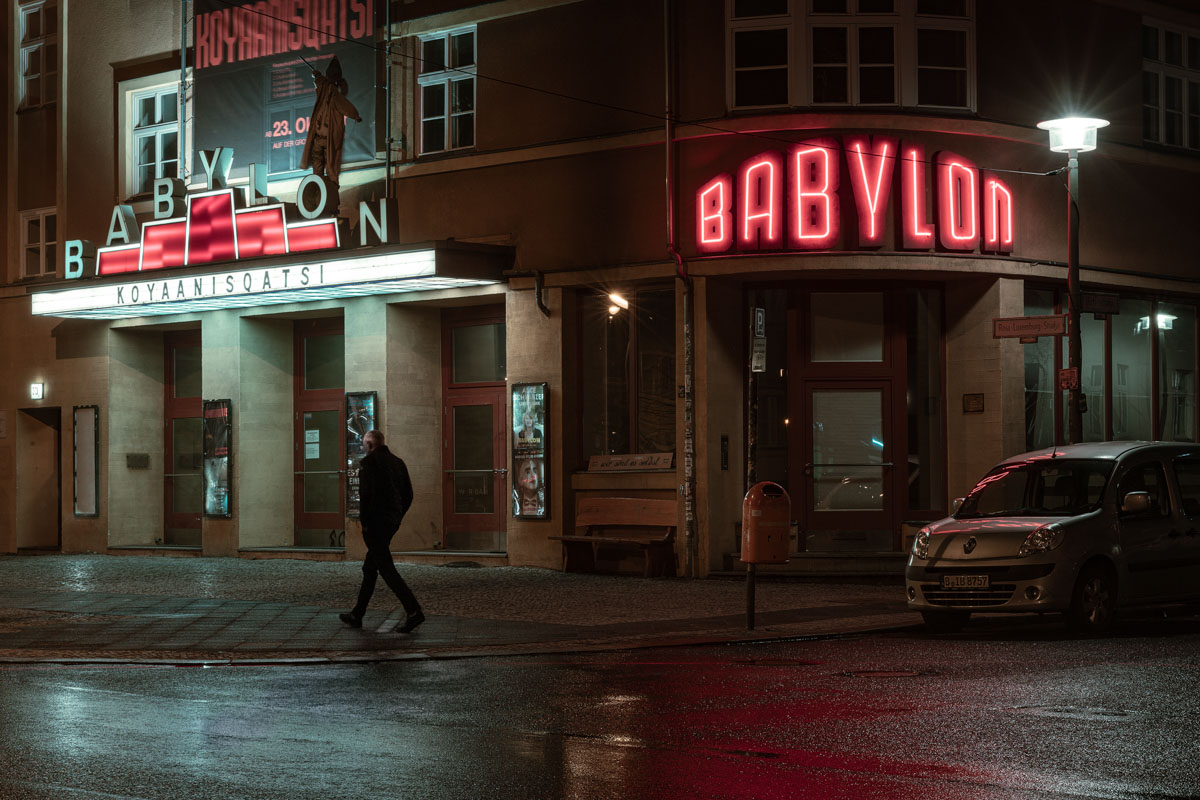 a person walking on a street in front of a building with neon signs