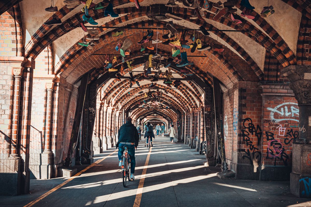 a person riding a bicycle under a brick tunnel with shoes from ceiling