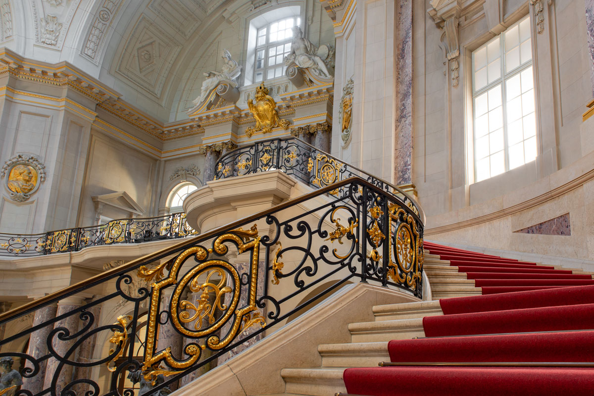 a staircase with red carpet and gold railing