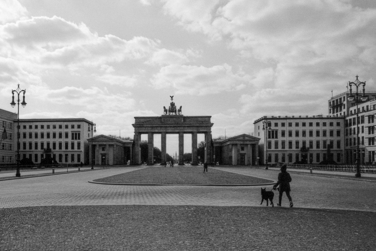 a person walking a dog in front of a large stone structure